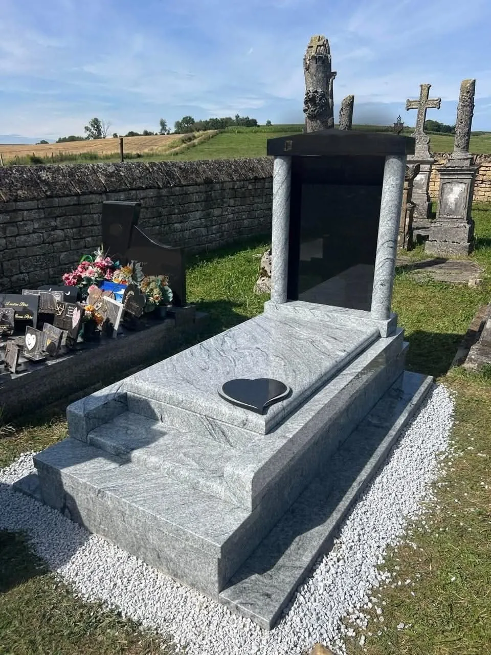 Vue d'ensemble d'un monument funéraire en granite gris posé dans un cimetière paysager