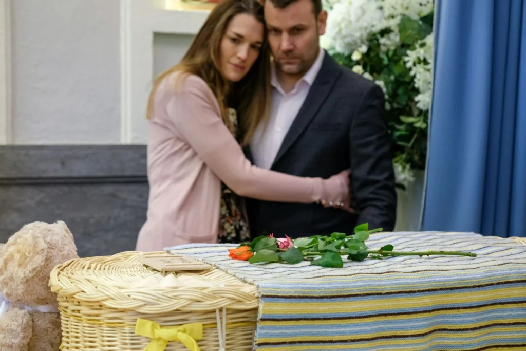 Couple se recueillant devant un cerceuil, illustrant la prévoyance obsèques